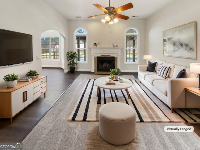 living room with dark wood-type flooring, a fireplace, plenty of natural light, and visible vents