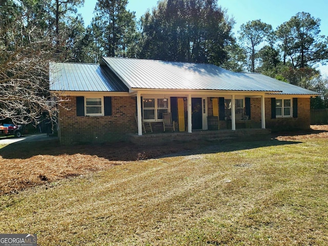 single story home featuring covered porch, a front yard, metal roof, and brick siding