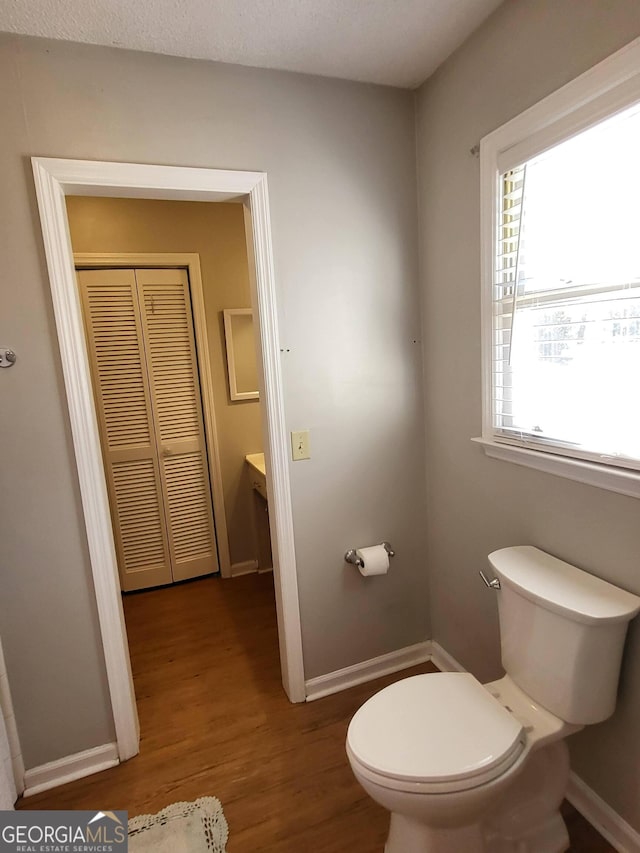 bathroom with baseboards, toilet, and wood finished floors