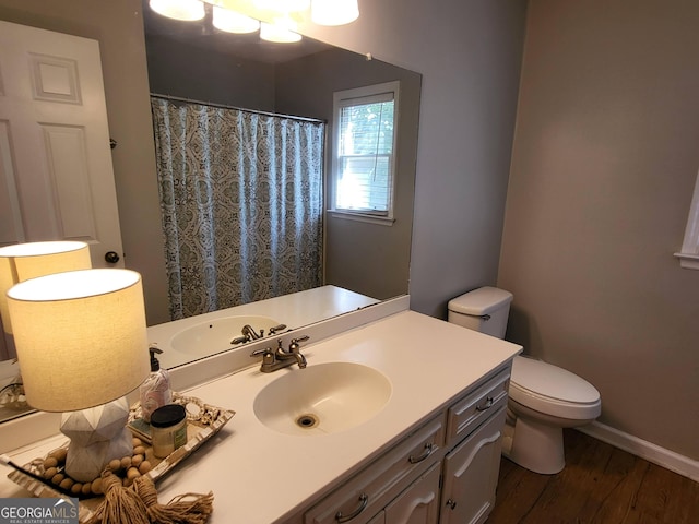 bathroom with a shower with shower curtain, toilet, vanity, wood finished floors, and baseboards