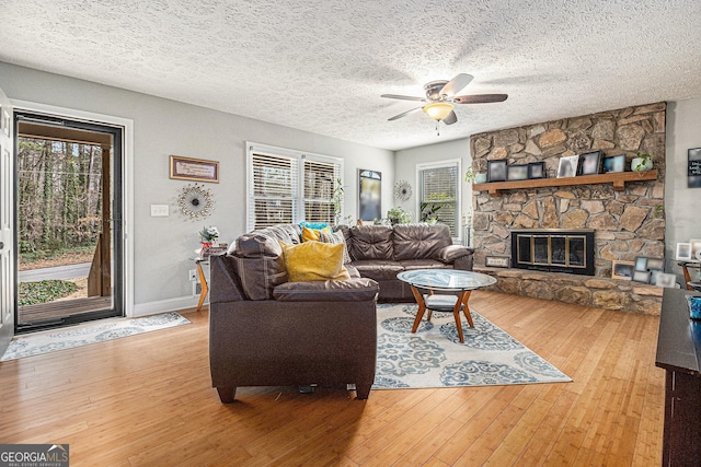 living area with a wealth of natural light, a fireplace, and light wood-style flooring