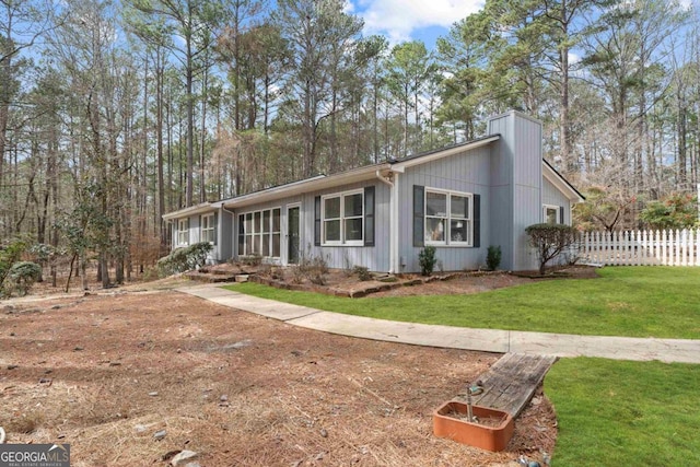 view of front of home with fence, a chimney, and a front lawn