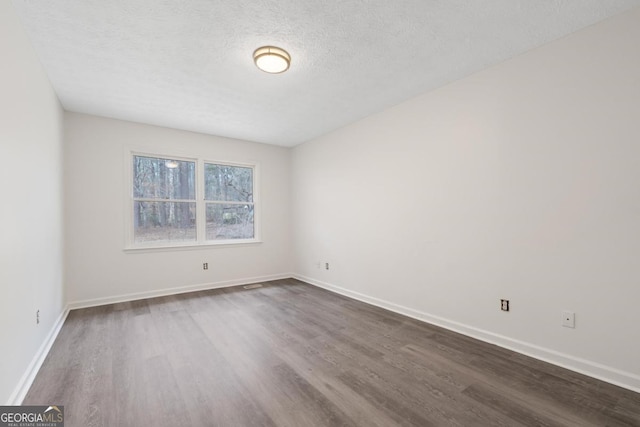 unfurnished room featuring dark wood-style floors, a textured ceiling, and baseboards