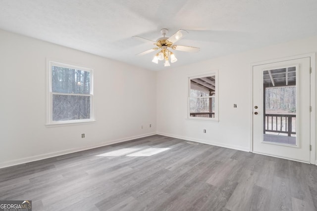 empty room with ceiling fan, baseboards, and wood finished floors