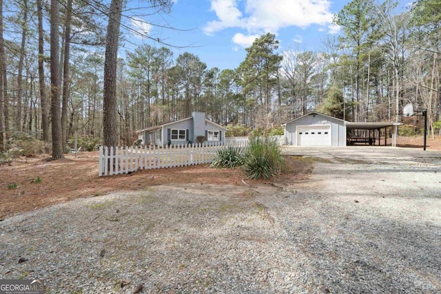 view of front of house with fence, driveway, and an outdoor structure