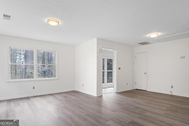 empty room featuring dark wood-style floors, baseboards, visible vents, and a textured ceiling