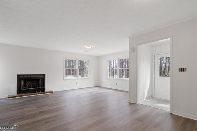 unfurnished living room featuring baseboards, dark wood-style flooring, crown molding, a textured ceiling, and a brick fireplace