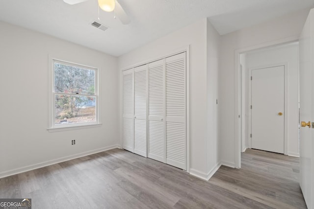 unfurnished bedroom with a closet, visible vents, a ceiling fan, light wood-type flooring, and baseboards