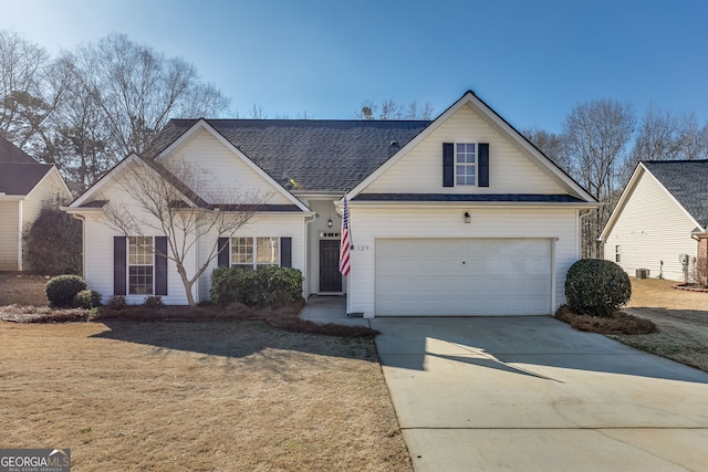 view of front of home featuring a shingled roof, a front lawn, and concrete driveway