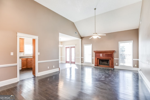 unfurnished living room with a fireplace with raised hearth, dark wood-style flooring, plenty of natural light, and visible vents