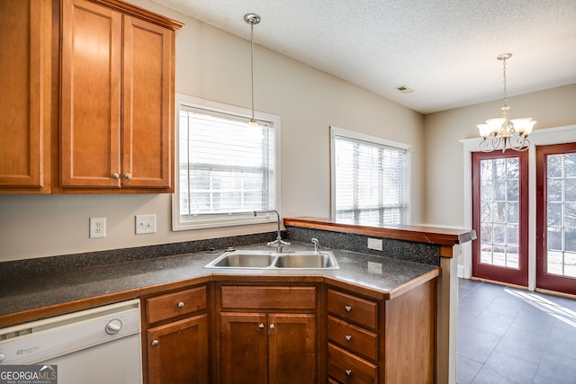 kitchen with white dishwasher, a peninsula, a sink, brown cabinetry, and dark countertops