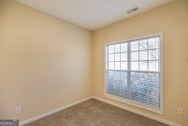 spare room featuring carpet, visible vents, and baseboards