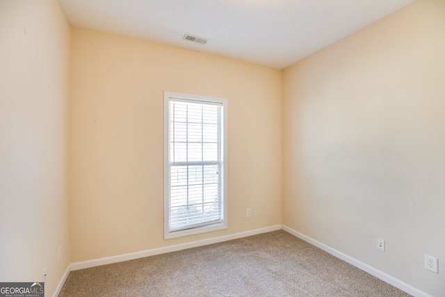 unfurnished room with carpet, visible vents, and baseboards