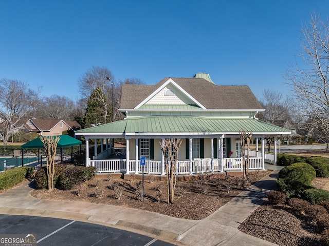 farmhouse inspired home featuring metal roof, a porch, and a standing seam roof