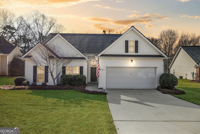 view of front of house with a garage, roof with shingles, a lawn, and concrete driveway