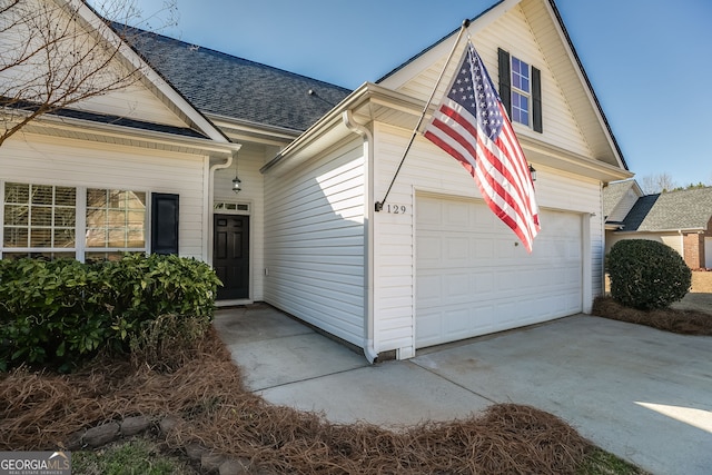 view of home's exterior featuring driveway and a shingled roof