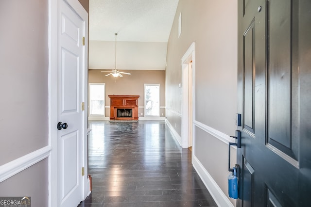 hall with a textured ceiling, baseboards, vaulted ceiling, and dark wood-type flooring