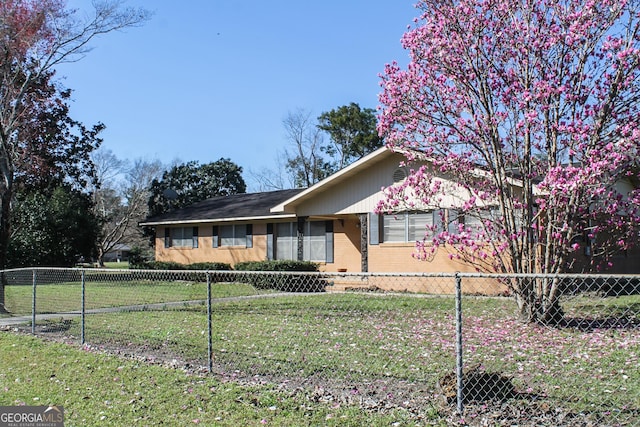 ranch-style home with a fenced front yard, a front lawn, and brick siding