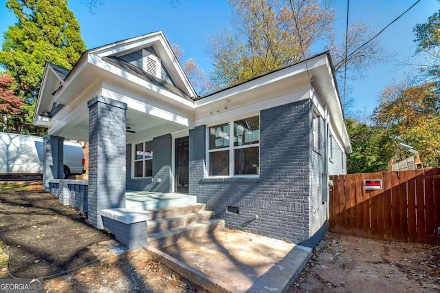 view of front facade featuring brick siding, crawl space, and fence