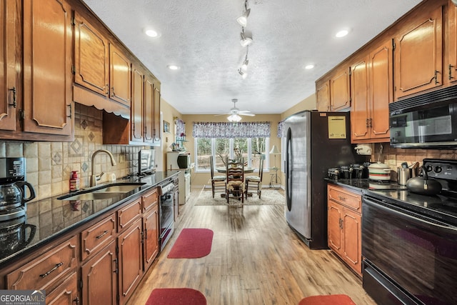 kitchen with arched walkways, light wood-style flooring, a sink, black appliances, and brown cabinetry