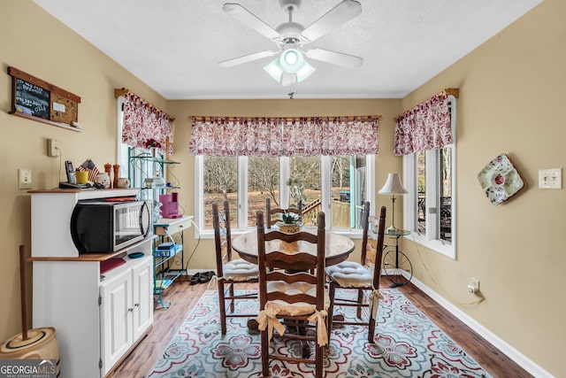 dining room with light wood-style floors, ceiling fan, baseboards, and a textured ceiling