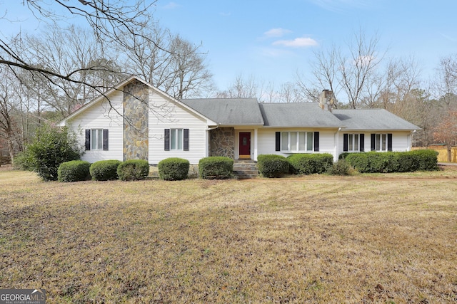 ranch-style home featuring stone siding, roof with shingles, a chimney, and a front yard