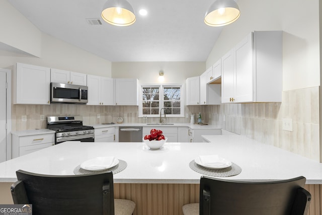 kitchen featuring light countertops, appliances with stainless steel finishes, a breakfast bar area, and white cabinetry