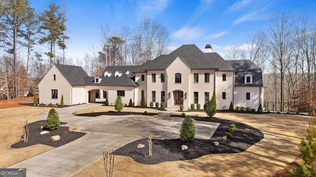 french country style house featuring curved driveway and a chimney