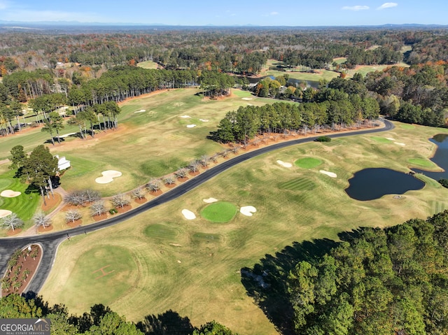 drone / aerial view featuring view of golf course, a water view, and a view of trees