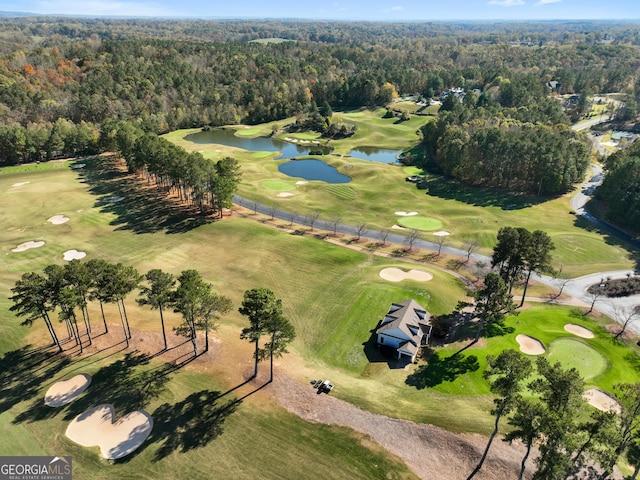 drone / aerial view featuring a water view, a wooded view, and golf course view