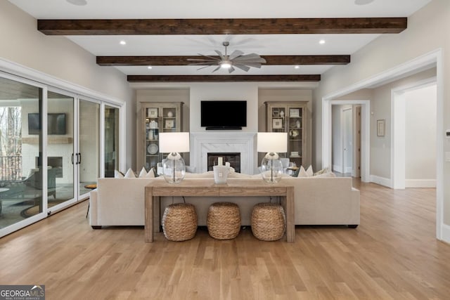 living room featuring ceiling fan, light wood-style flooring, baseboards, and a premium fireplace