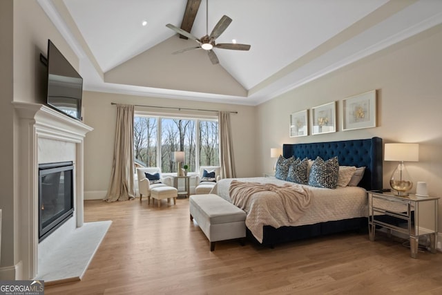 bedroom with light wood-style flooring, high vaulted ceiling, beamed ceiling, and a high end fireplace