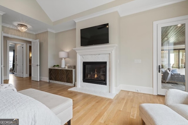 bedroom with lofted ceiling, a premium fireplace, wood finished floors, and baseboards