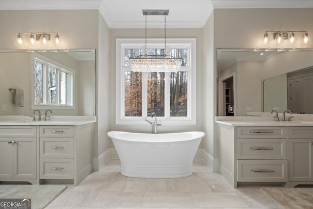 full bath featuring baseboards, two vanities, crown molding, a freestanding bath, and a sink