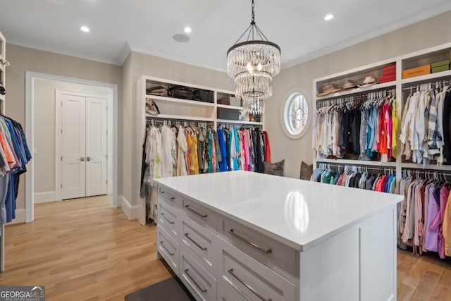 walk in closet featuring light wood-type flooring and a notable chandelier