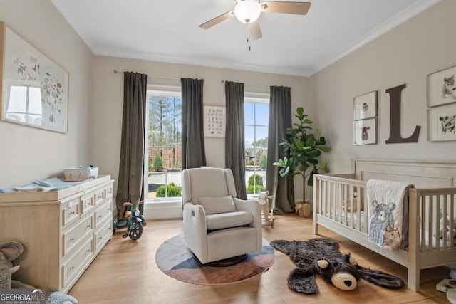 bedroom featuring light wood-type flooring, a nursery area, and multiple windows