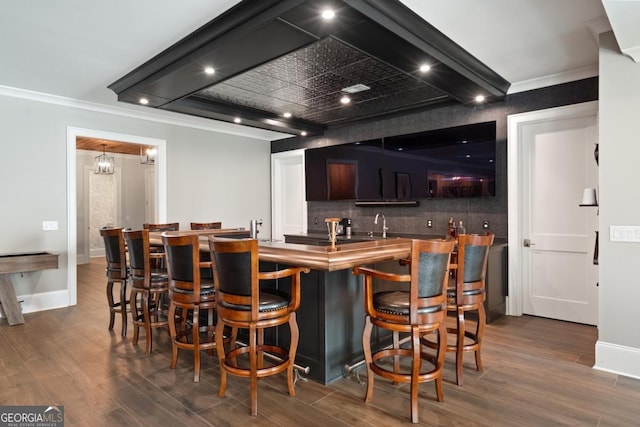 bar with ornamental molding, dark wood-type flooring, backsplash, and baseboards