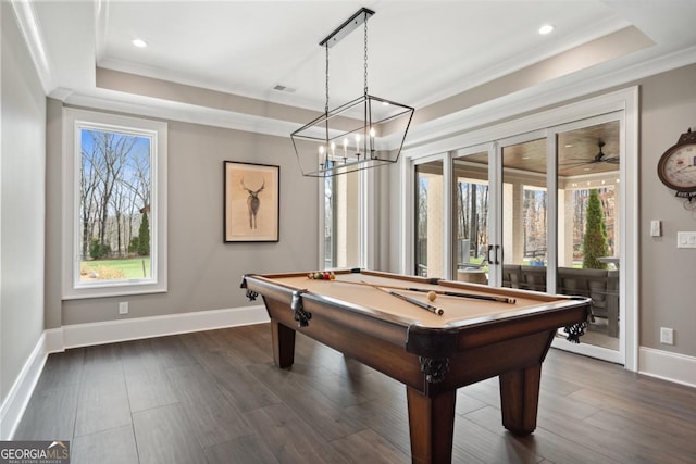 game room with dark wood-style floors, a raised ceiling, and crown molding