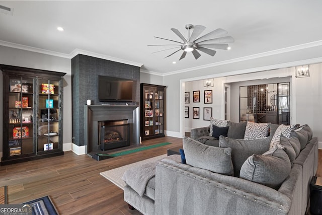 living area with a large fireplace, baseboards, dark wood-type flooring, and ornamental molding