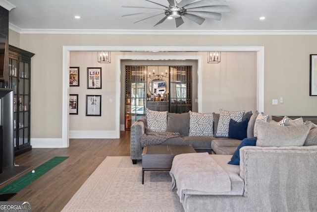 living area with recessed lighting, ceiling fan with notable chandelier, wood finished floors, baseboards, and crown molding