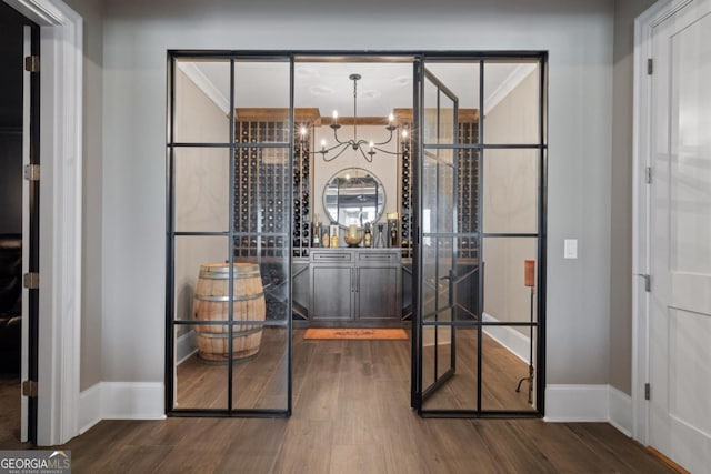 wine area featuring a chandelier, baseboards, and wood finished floors