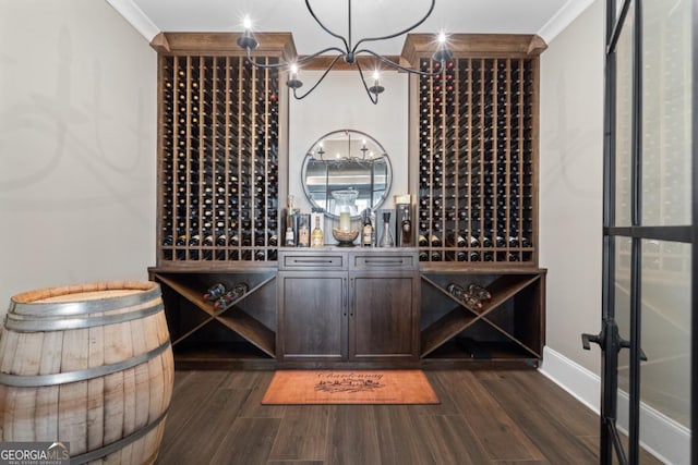 wine cellar with ornamental molding, dark wood-style flooring, a notable chandelier, and baseboards