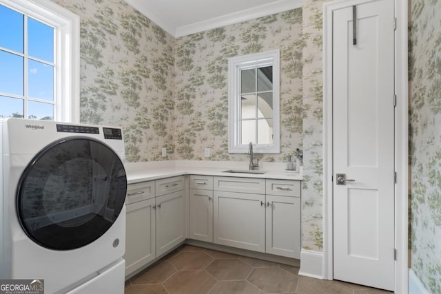 washroom featuring cabinet space, a sink, washer / dryer, and wallpapered walls