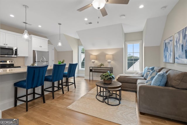 living room featuring light wood-style floors, baseboards, a ceiling fan, and recessed lighting