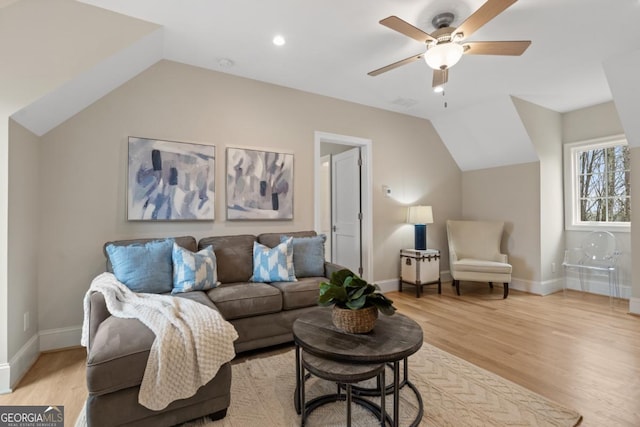 living room with light wood-style floors, vaulted ceiling, and baseboards