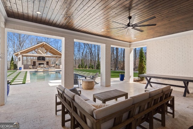 view of patio with a ceiling fan, a pool with connected hot tub, and an outdoor living space with a fireplace