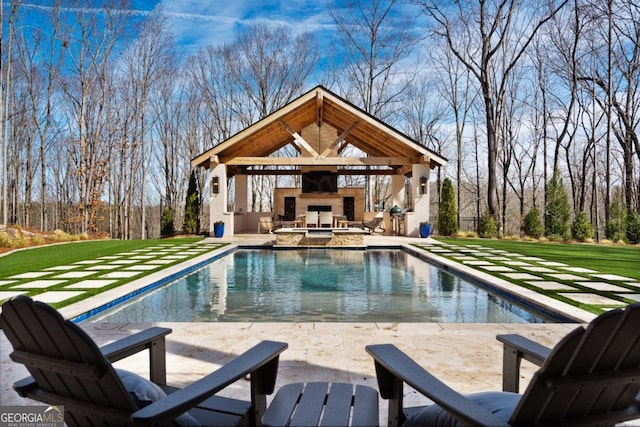 pool with a patio area, an outdoor stone fireplace, and a yard