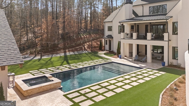 back of house with a patio, a shingled roof, a standing seam roof, metal roof, and a balcony