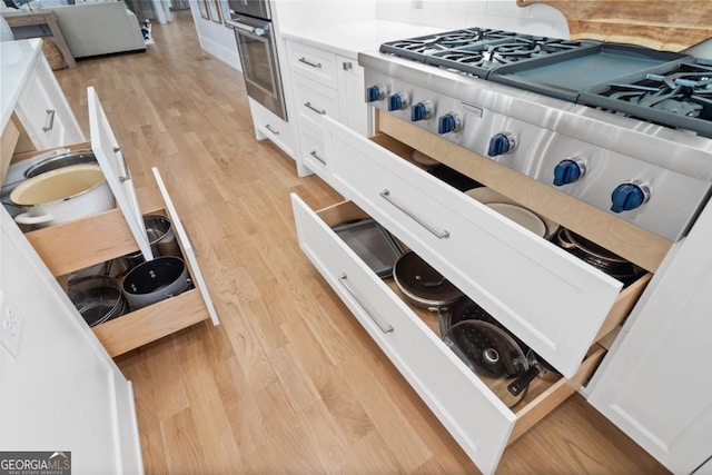 interior space featuring light wood-type flooring, white cabinets, and stainless steel oven