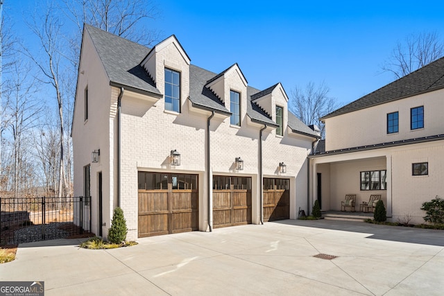 view of side of property with concrete driveway, brick siding, and roof with shingles